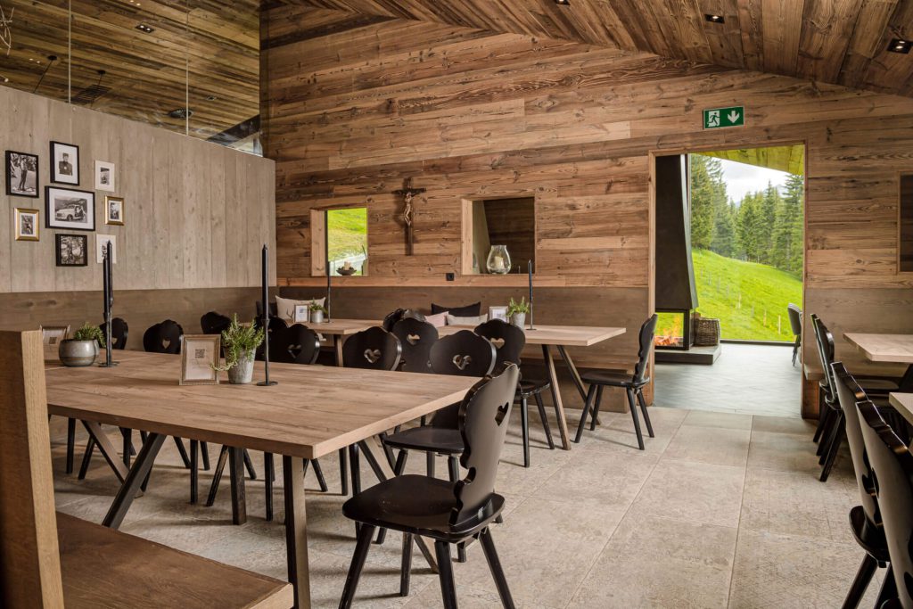 Gemütliches Restaurantinterieur mit Holztischen, Stühlen und Blick ins Grüne.