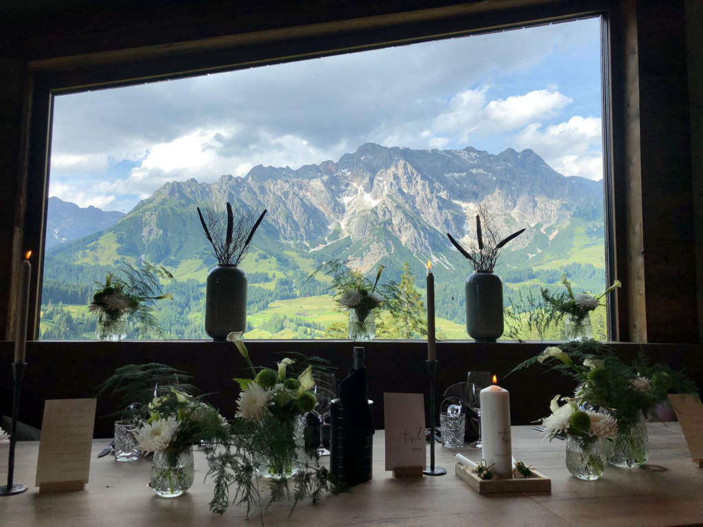 Festlich gedeckter Tisch mit Blumen Kerzen vor Panoramafenster Alpenblick Hochkönig