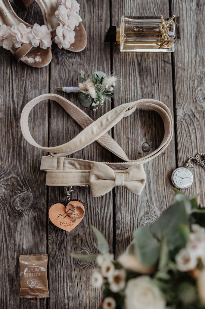 Beige Fliege mit Holzanhänger, Hochzeitsaccessoires auf rustikalem Holztisch